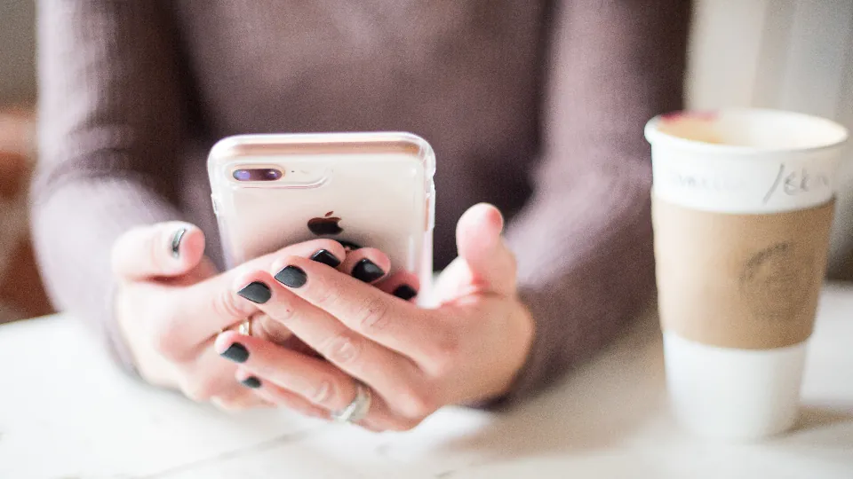 Hands holding a smartphone with coffee, browsing health guides