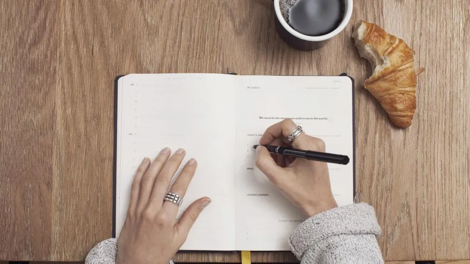Hand writing notes in a notebook while researching a health article
