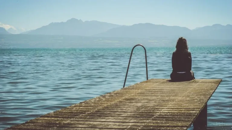 Woman sitting calmly on a wooden pier by a lake