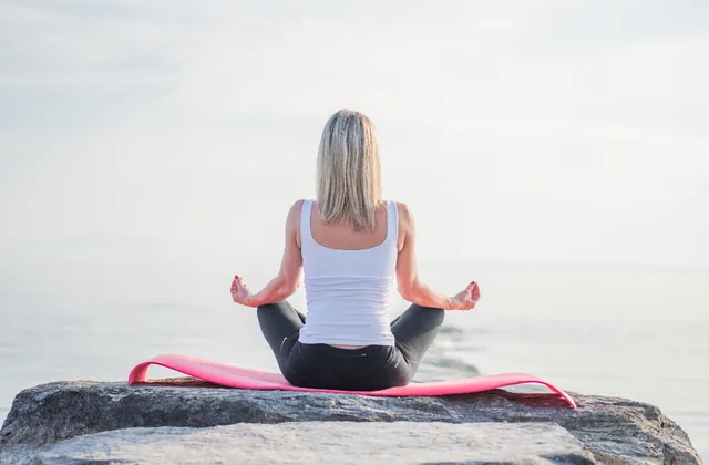 Woman meditating by the sea for mental wellbeing